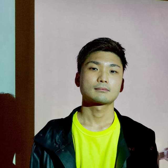 黒いパーカーを着た短髪の男性のバストアップ